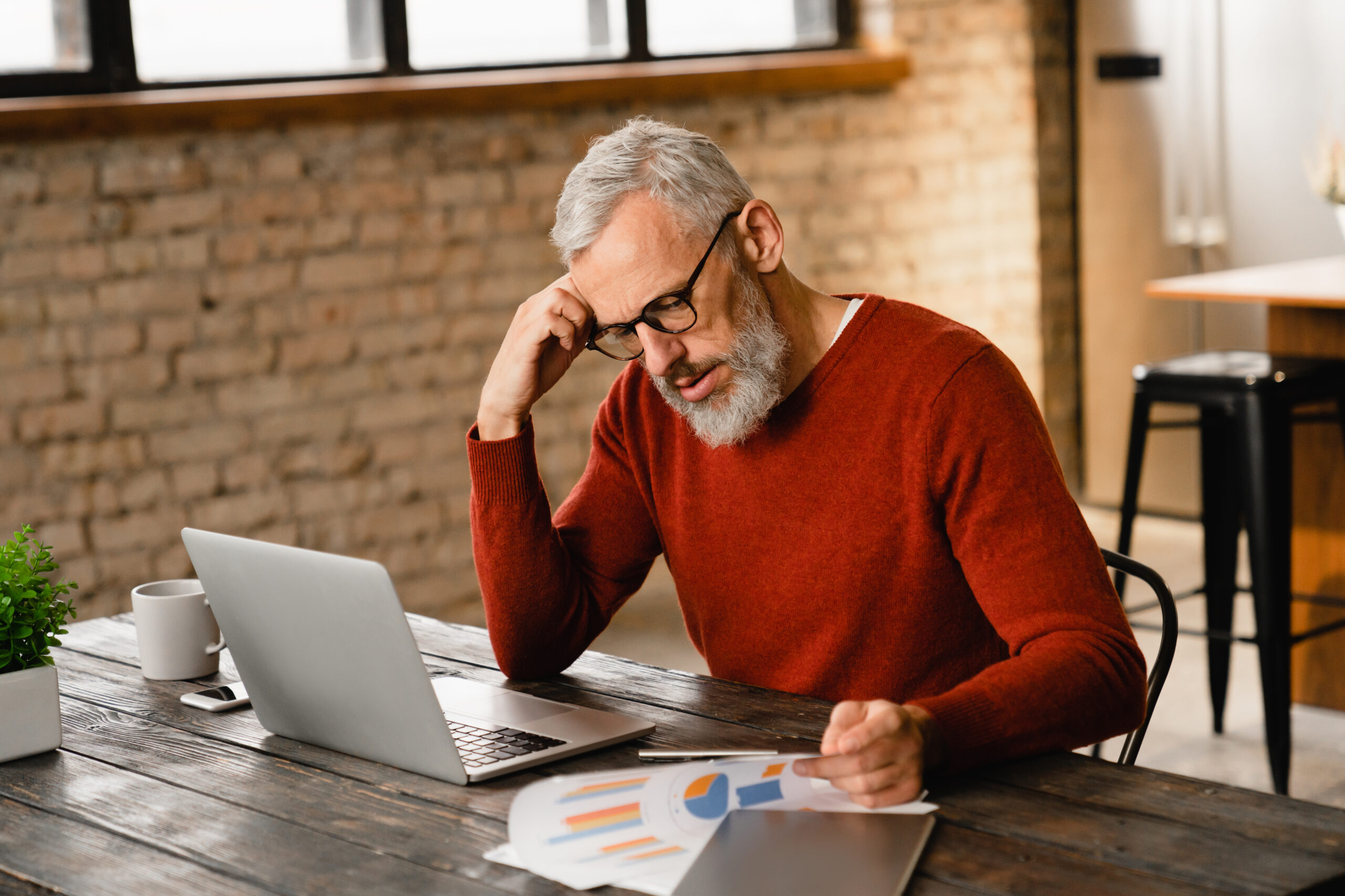 Older man appearing stressed over paperwork