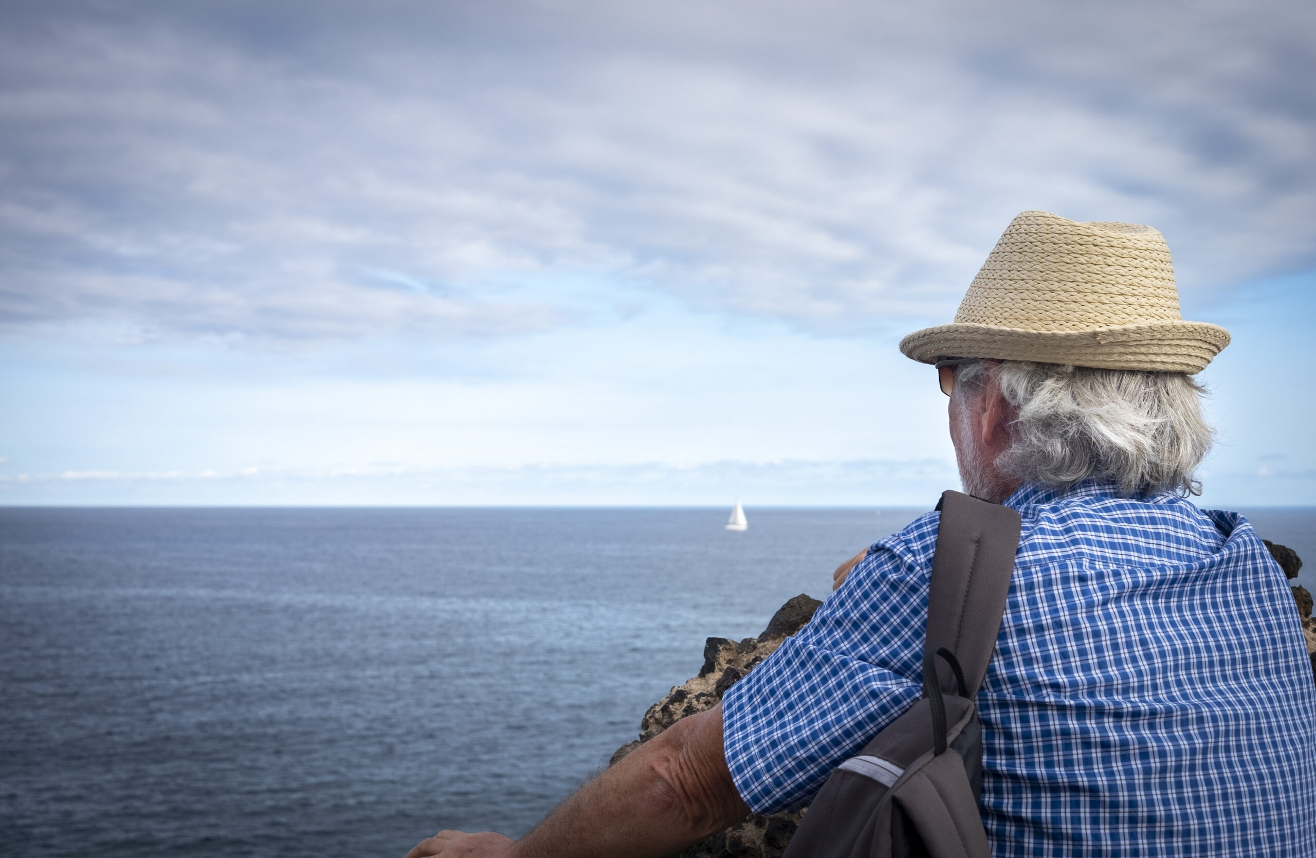 Person looking out over the water at a sailboat